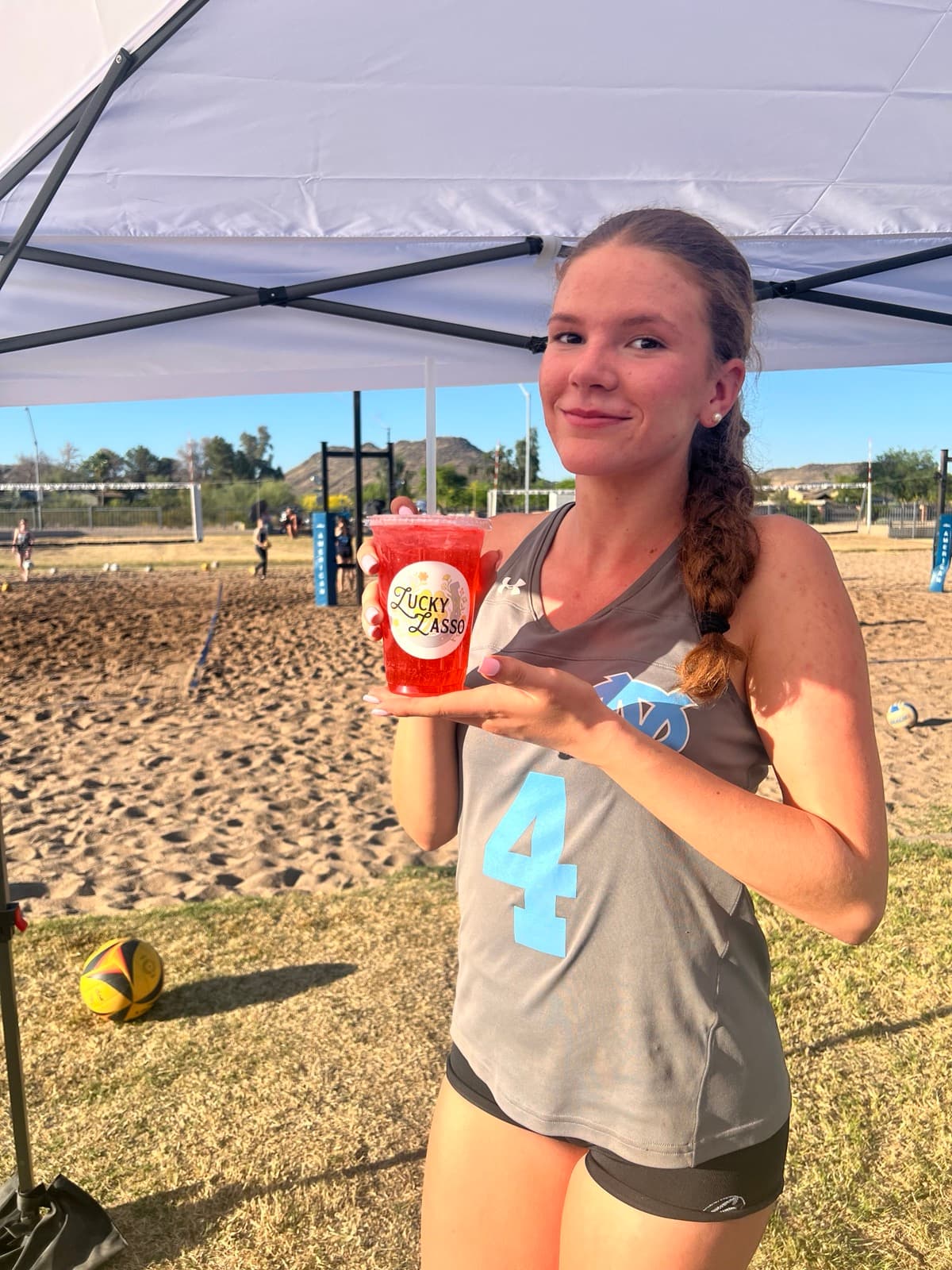 Volleyball player enjoying a Lucky Lasso drink at beach volleyball